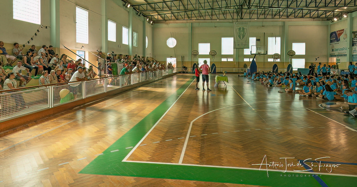 Indoor sports hall with a basketball court, spectators, and sports equipment.