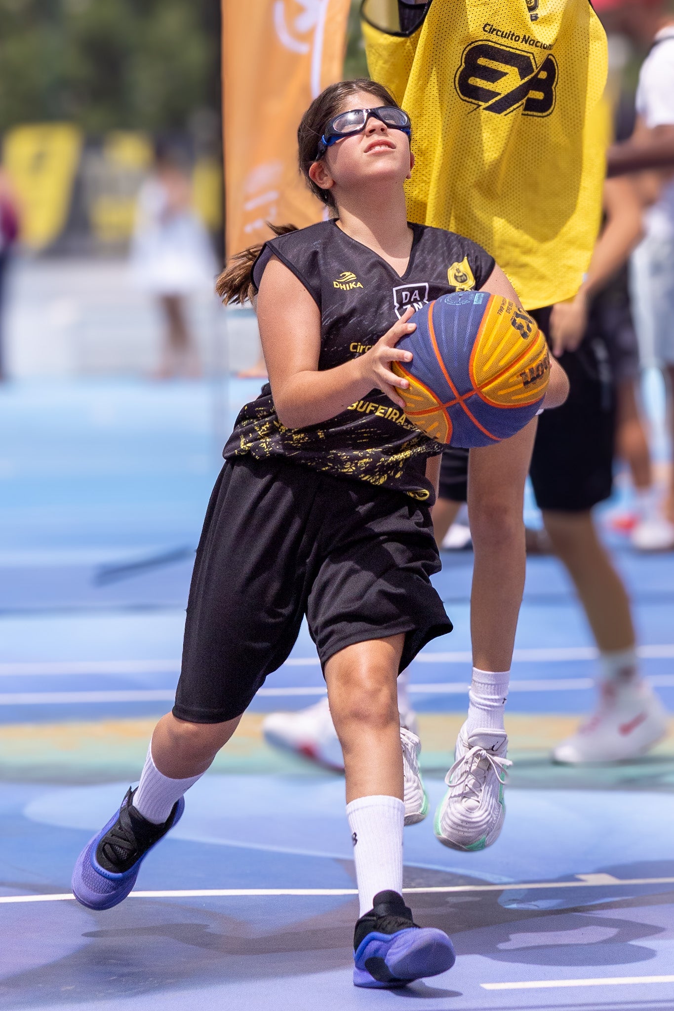 Person playing basketball on an outdoor court with a visible brand logo.