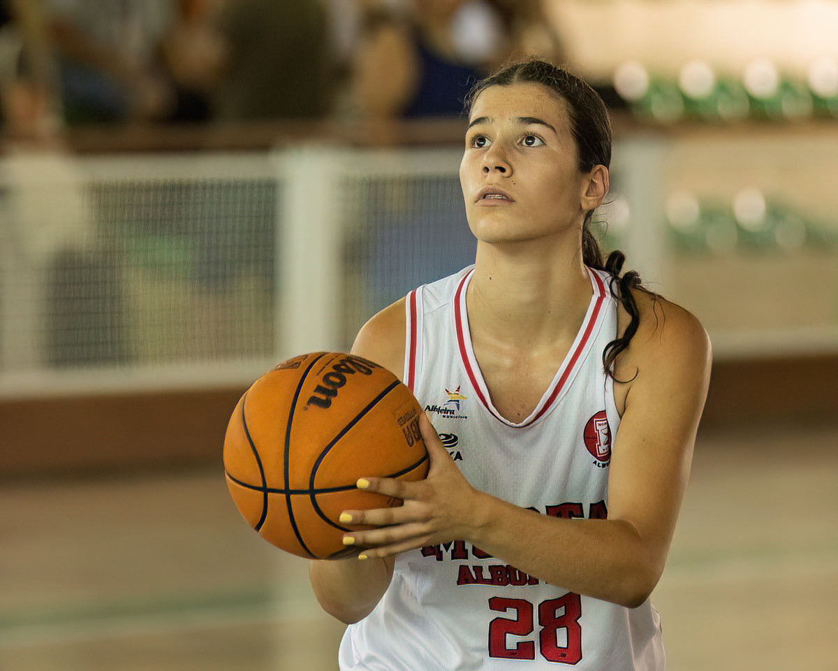 Woman holding a basketball on a court with a blurred background