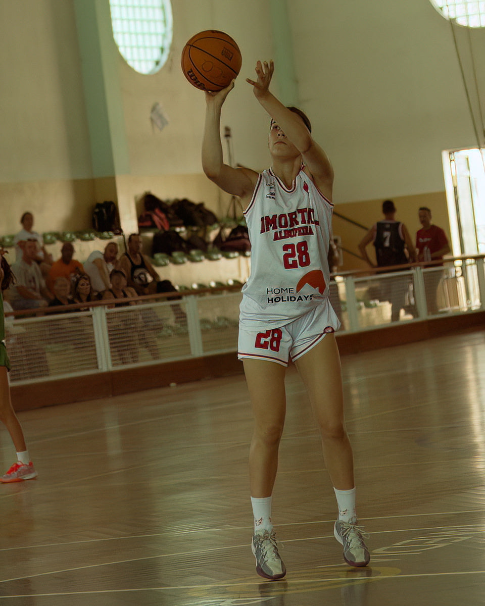 Person playing basketball in a gymnasium with spectators in the background