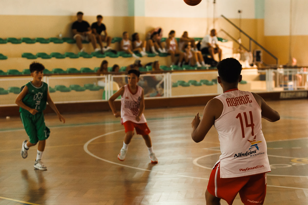 Three basketball players in action on a court with spectators in the background.