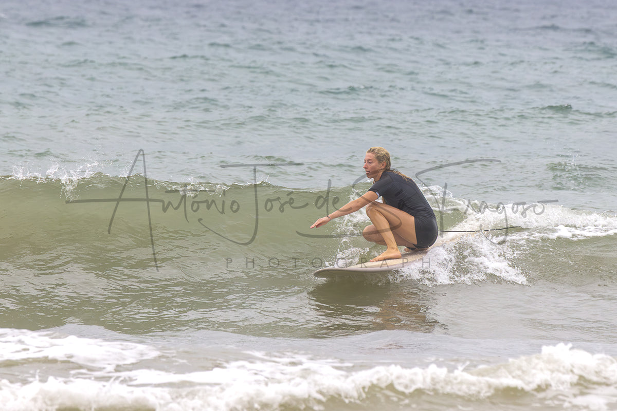 A surfer in a black wetsuit crouches on a surfboard in the ocean, with a large cursive watermark reading 'Antonio José de S. Fragoso Photography' across the center.
