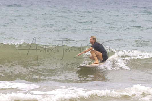 A surfer in a black wetsuit crouches on a surfboard in the ocean, with a large cursive watermark reading 'Antonio José de S. Fragoso Photography' across the center.