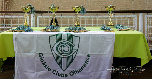 Table with trophies on a tablecloth featuring a logo, likely of a sports club.