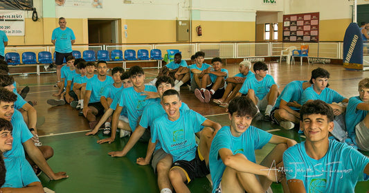 Group of young men in blue shirts sitting on a basketball court.