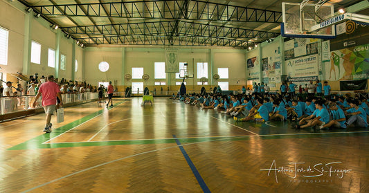 Basketball game in progress with players on a court, spectators, and advertisements on the walls.