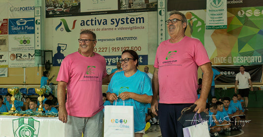 Three people standing on a podium with banners and advertisements in the background