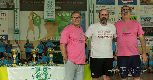 Three men standing together at an event with trophies and banners in the background