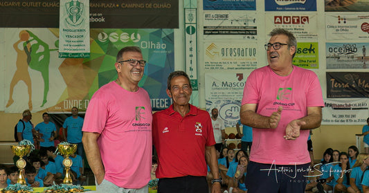 Three men standing together with trophies in front of a wall with various advertisements