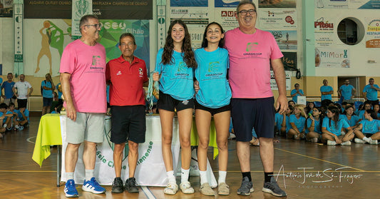 Two pairs of twins in sports uniforms standing with two adults on a sports court.