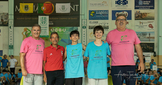 Group of people posing together in a sports hall with various banners on the wall.