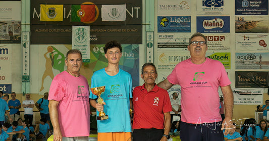 Four men standing together with a trophy in an indoor sports arena.