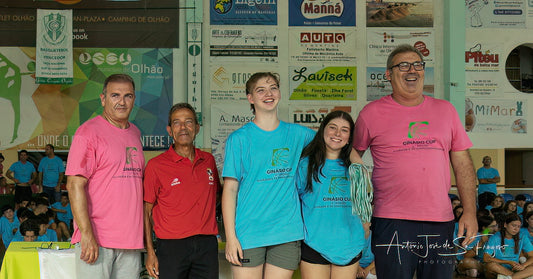 Group of people posing for a photo in front of a colorful background with various advertisements.