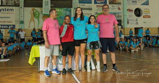 Group of people posing for a photo in a sports hall with children in the background