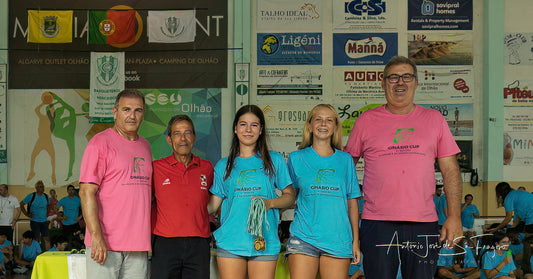 Group of people posing together with sports club t-shirts in front of a wall with various advertisements.