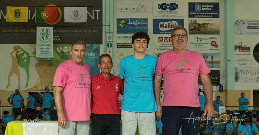 Four men standing together in front of a wall with various advertisements and flags.