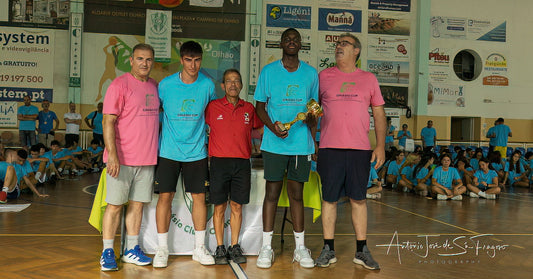 Group of people on a basketball court with a trophy, surrounded by spectators and advertisements.