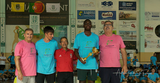 Group of people standing together with a trophy in an indoor sports facility.