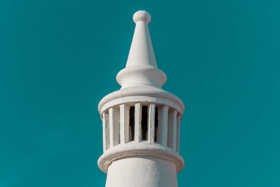 A white, conical Algarve chimney against a clear blue sky.