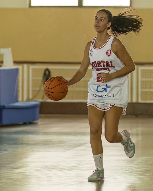 Woman in a basketball uniform dribbling a ball on a court