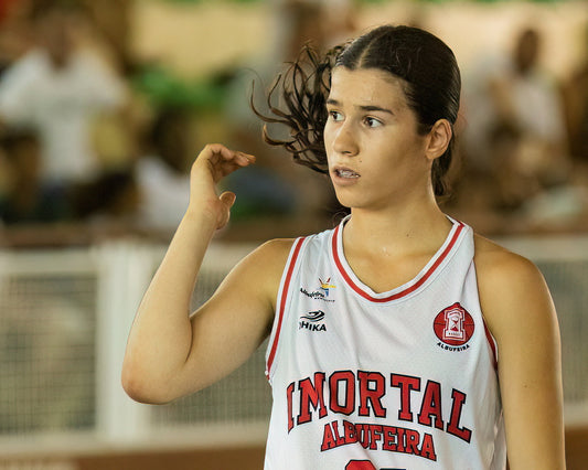 Woman in a basketball jersey with 'Mortal Albufeira' on a blurred background