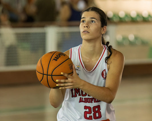 Young female basketball player holding a basketball on a court