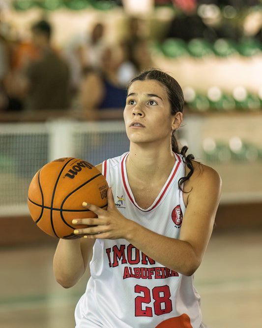 Basketball player holding a ball on a court with blurred spectators in the background