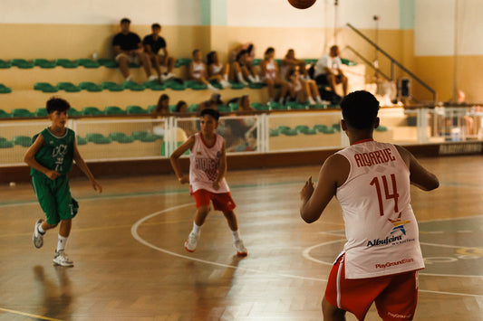 Three basketball players in action on a court with spectators in the background.